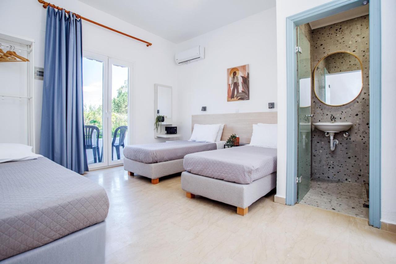 een slaapkamer met twee bedden, een wastafel en een spiegel bij Seaside Resorts in Kavos