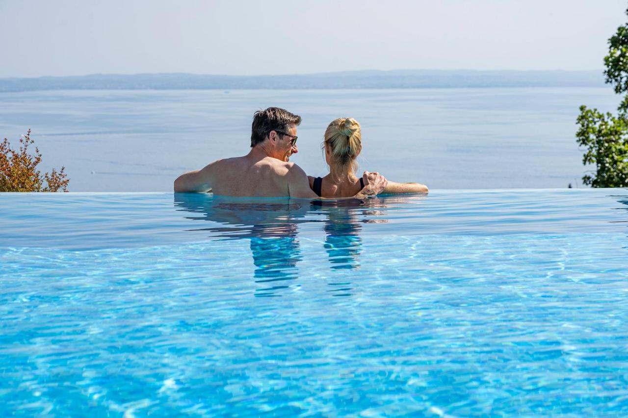 een man en een vrouw in een zwembad in het water bij Madrigale Panoramic Lifestyle & Soulful Hotel in Costermano
