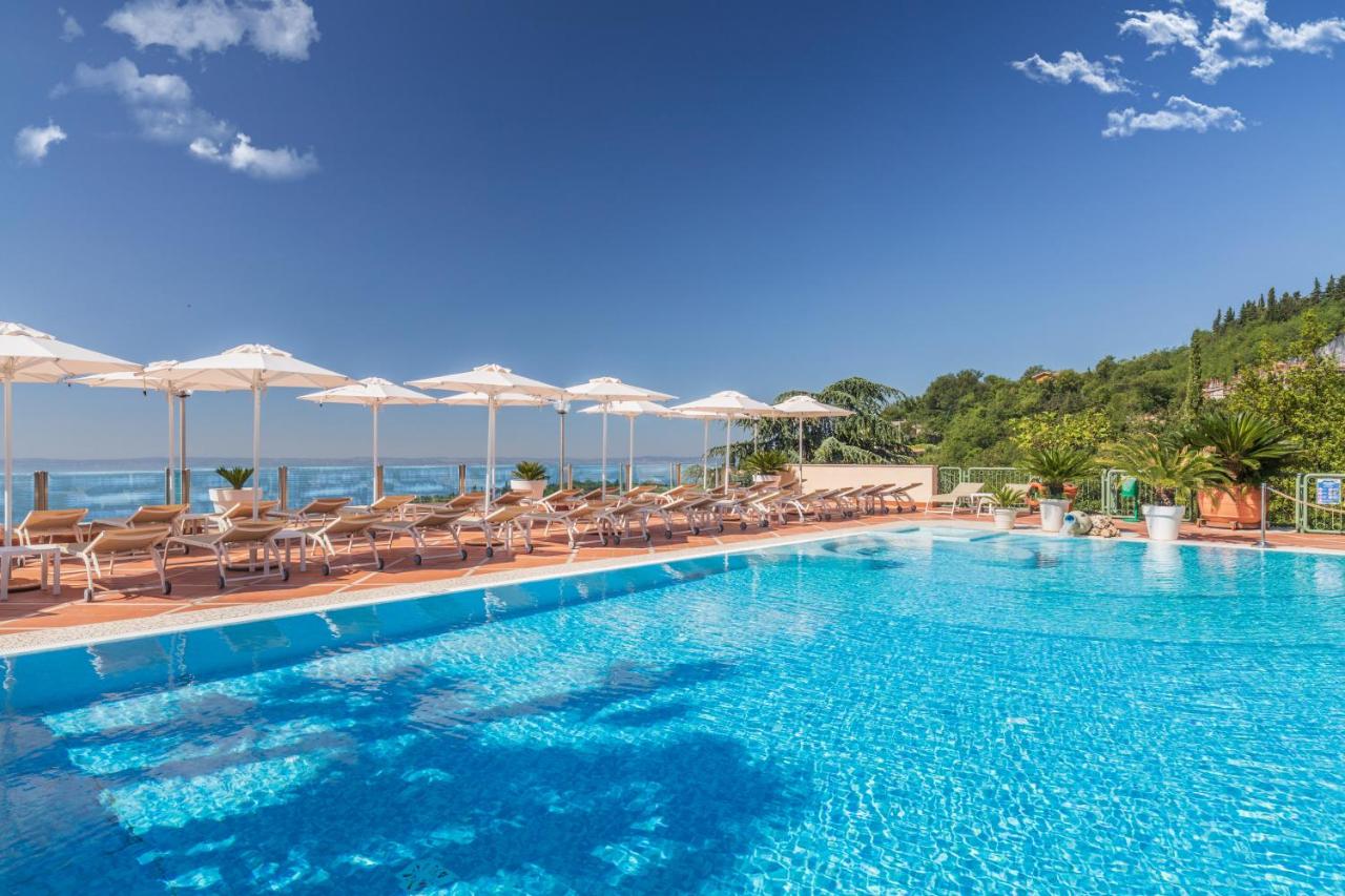 een groot zwembad met ligstoelen en parasols bij Madrigale Panoramic Lifestyle & Soulful Hotel in Costermano