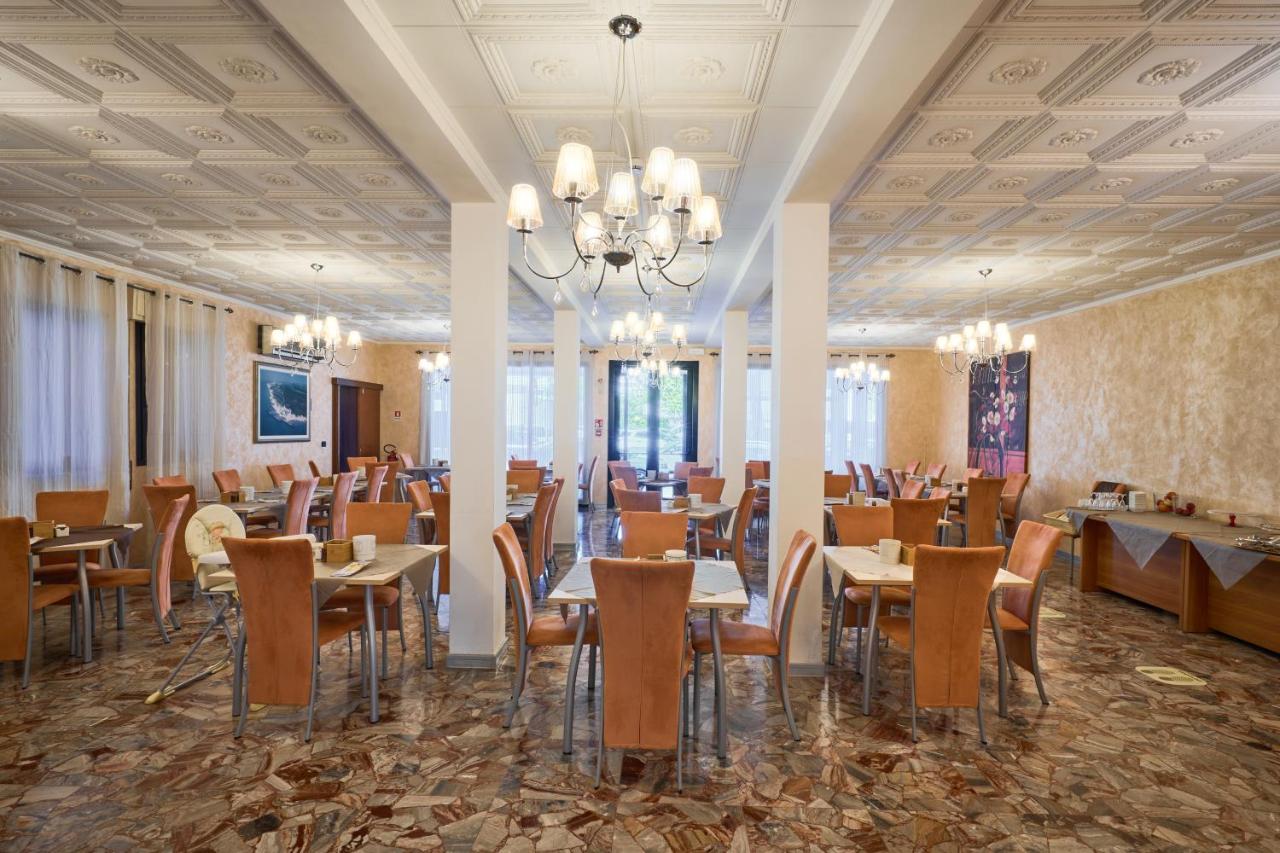 een eetkamer met tafels en stoelen en een kroonluchter bij Hotel Villa Del Mar in Bibione