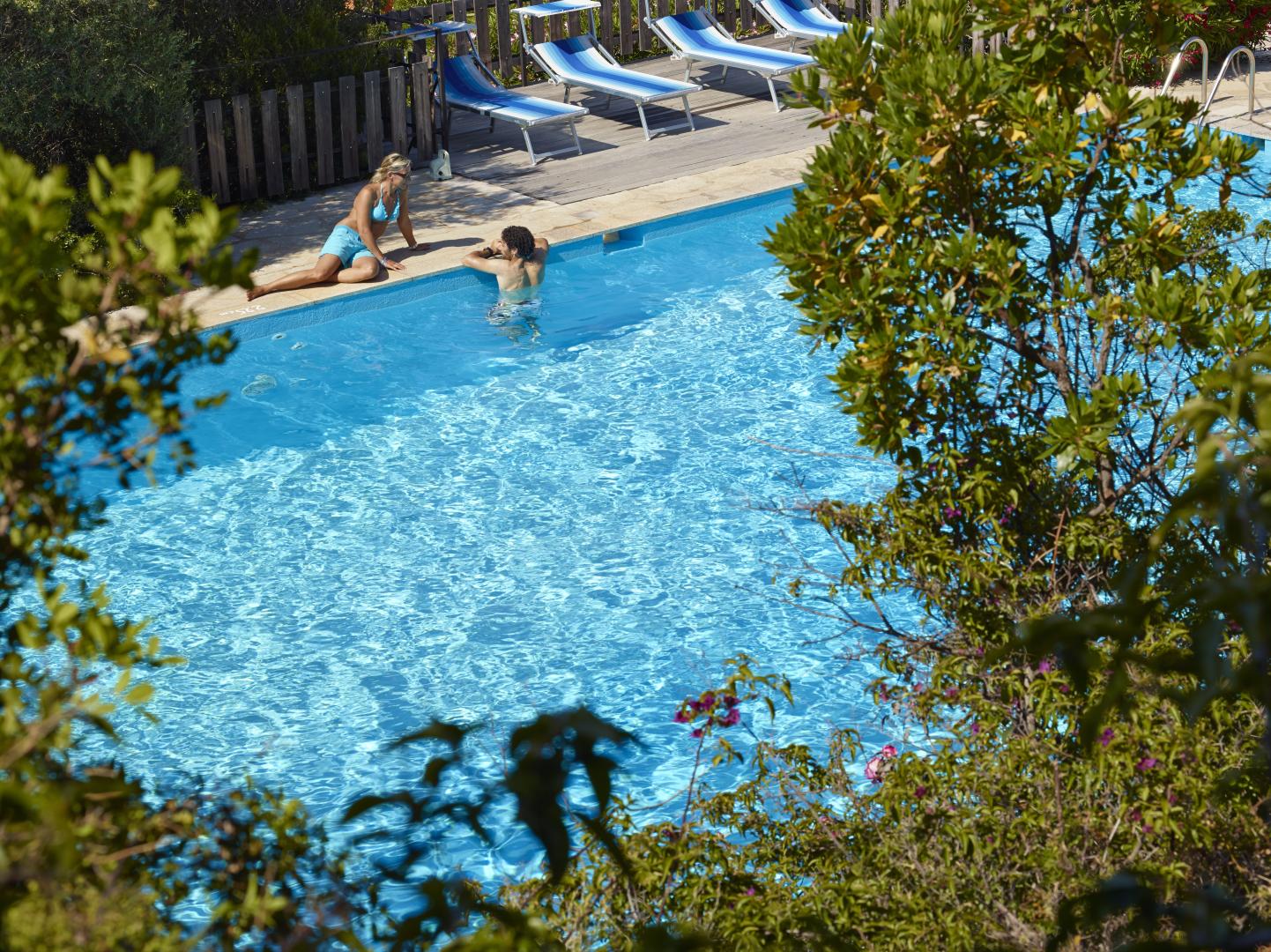 Zwembad omringd door palmbomen — Aparthotel Lu Nibareddu