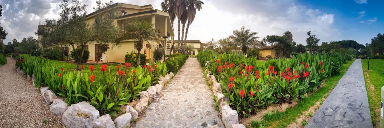 een tuin met rode bloemen voor een huis bij Horse Country Resort Congress & Spa - Hotel Castello in Arborea 