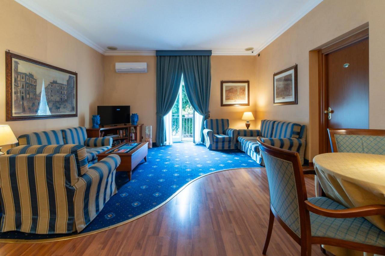 een hotelkamer met blauwe stoelen en een tafel en een woonkamer bij Massimo Plaza Hotel in Palermo
