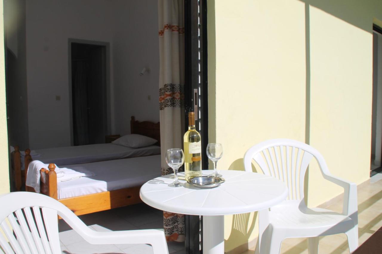 een tafel en stoelen met een fles wijn en een bed bij Kavos Central Gardens in Kavos