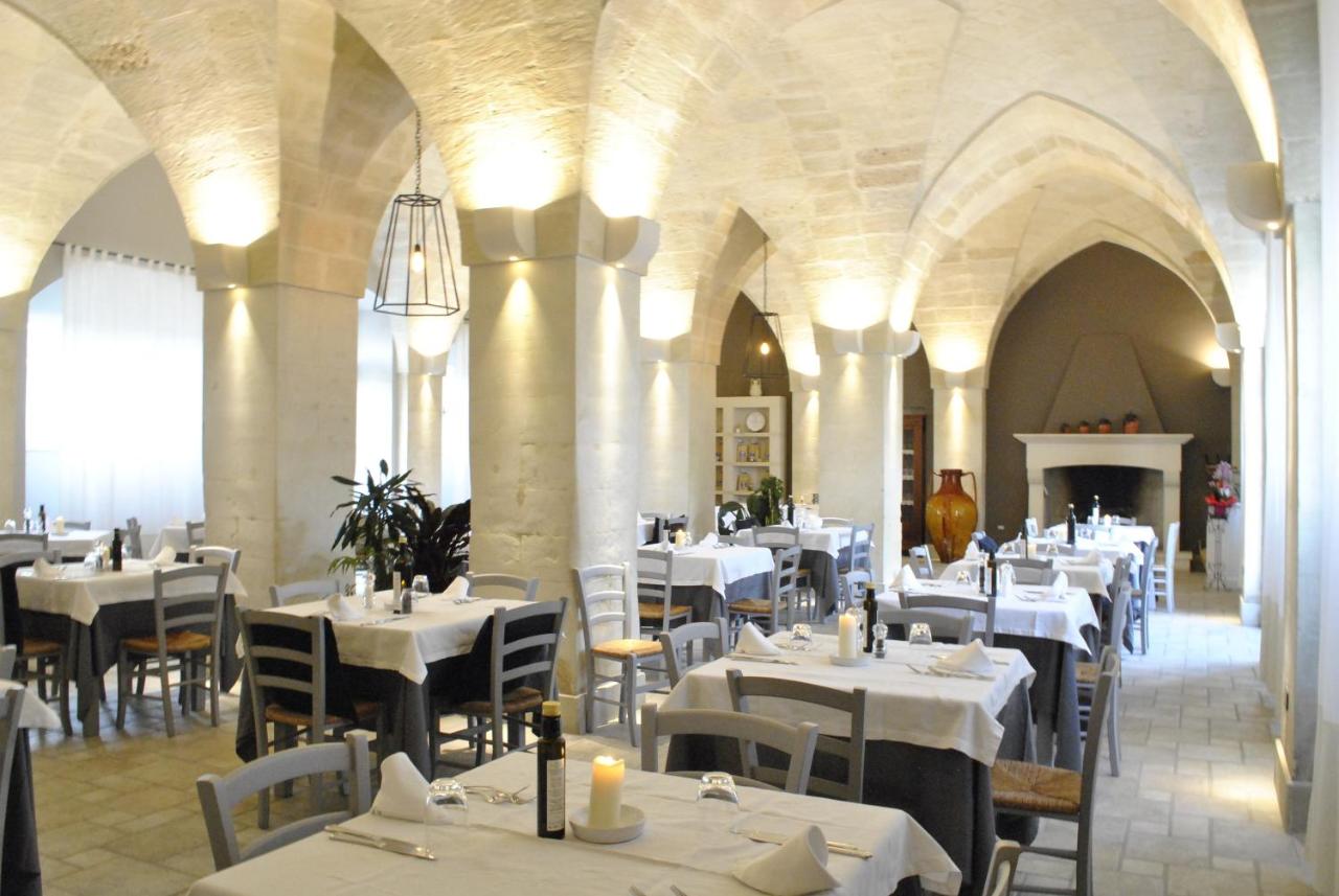 een restaurant met witte tafels en stoelen en een open haard bij Masseria Panareo in Otranto