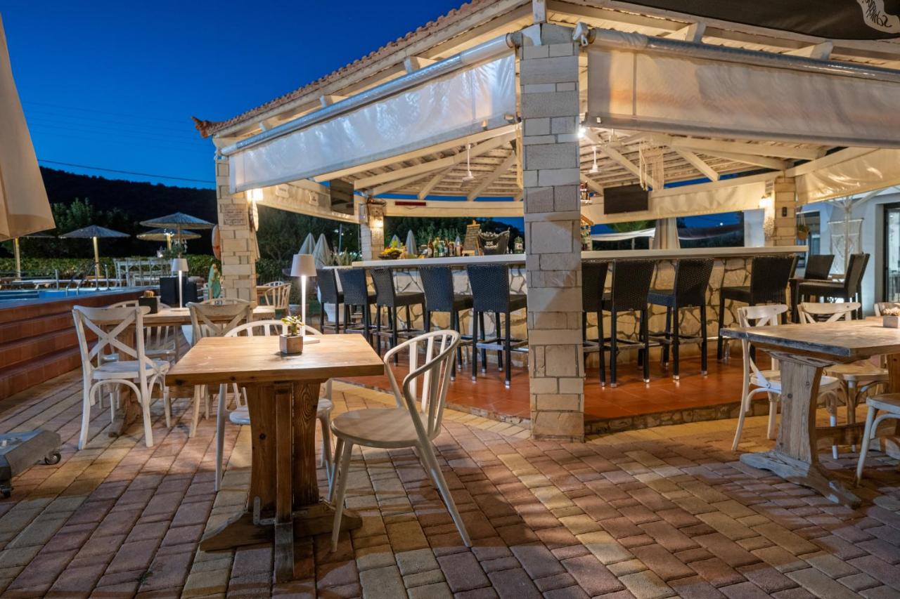 een terras met tafels en stoelen en een bar bij Nikos Apartments in Stalida