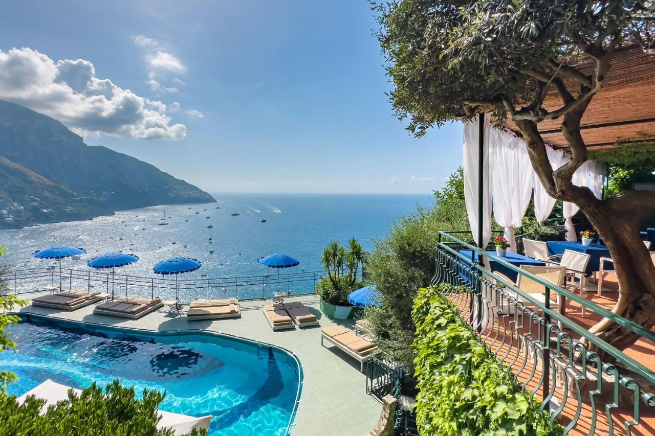 een zwembad met stoelen en parasols aan de oceaan bij Hotel Le Agavi in Positano