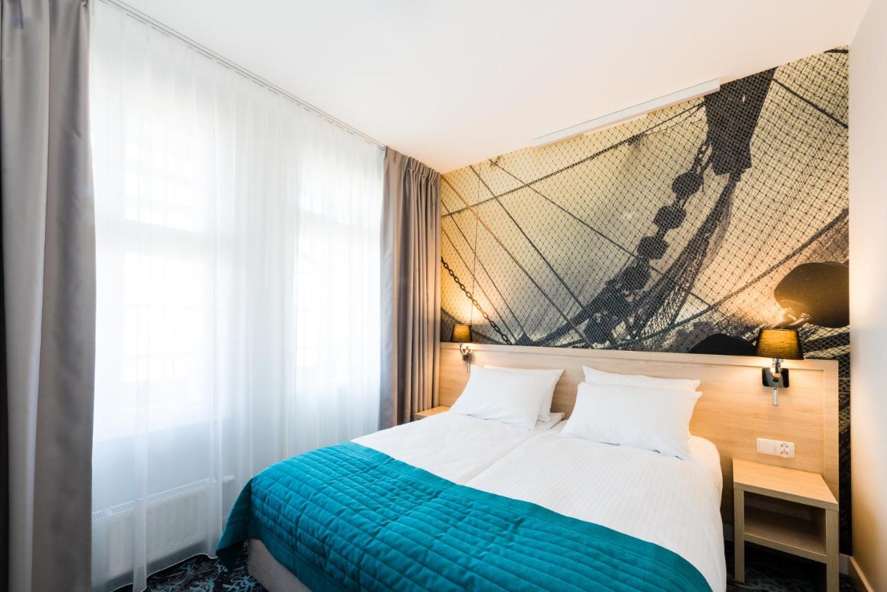 een slaapkamer met een bed en een schilderij aan de muur bij Hotel Eureka in Sopot
