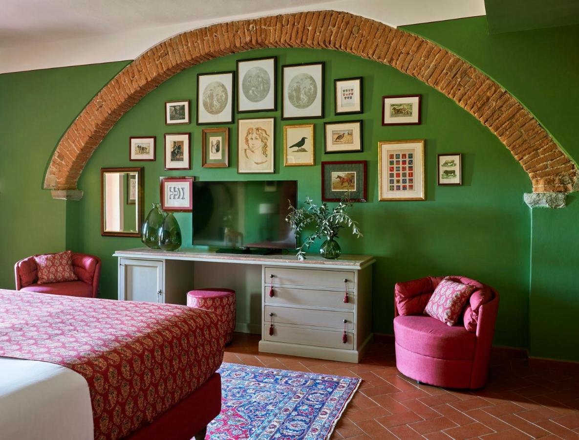 een slaapkamer met een groene muur, een bed en twee stoelen bij Hotel Tenuta di Artimino member of Meliá Collection in A
