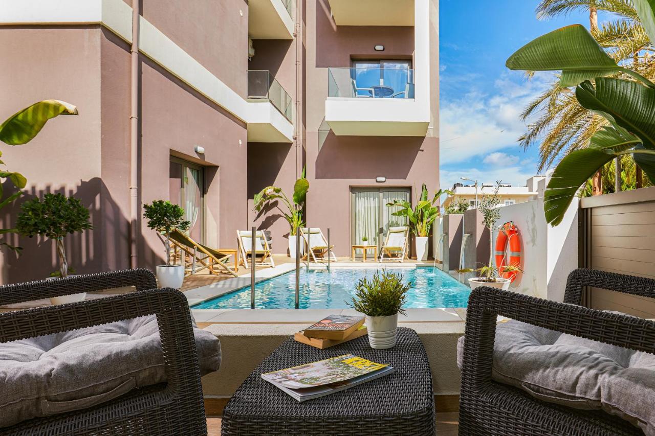 een terras met een tafel en stoelen en een zwembad bij Dionisos Hotel in Malia
