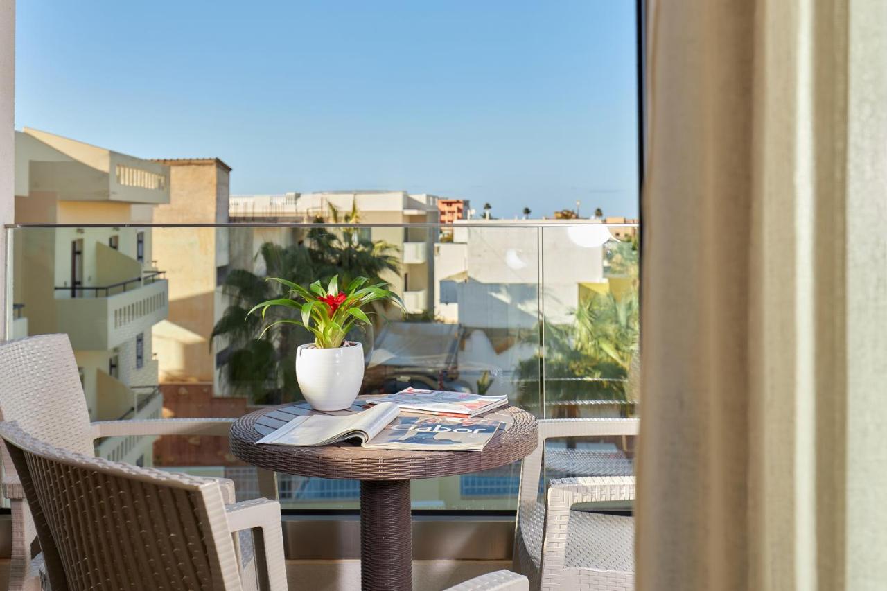 een tafel met een boek en een plant op een balkon bij Dionisos Hotel in Malia