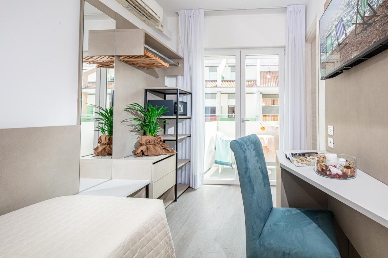 een kamer met een bed, een bureau en een stoel bij Hotel Pigalle in Lido di Jesolo
