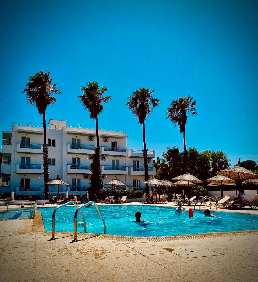 een zwembad met palmbomen en een hotel bij Elga Hotel & apartments in Kardamaina