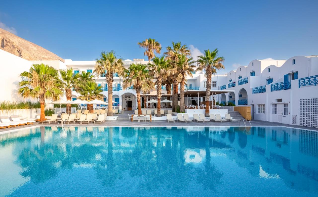een zwembad voor een hotel met palmbomen bij Kamari Beach Hotel in Kamari