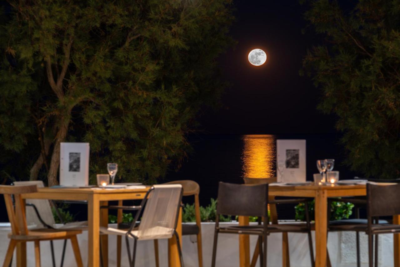 Twee tafels en stoelen met de maan op de achtergrond. bij Kamari Beach Hotel in Kamari