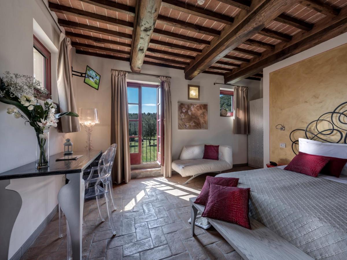 een slaapkamer met een bed, een tafel en een bank bij Hotel & Restaurant Casolare Le Terre Rosse in San Gimignano