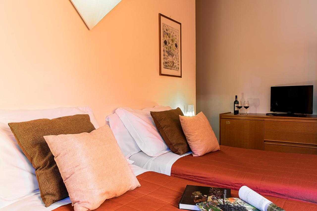 een slaapkamer met een bed met kussens en een tv bij La Vecchia Cartiera in Colle di Val d'Elsa