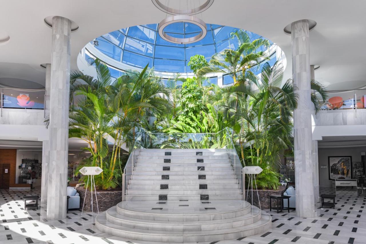 een lobby met een groot gebouw met palmbomen bij Elba Lanzarote Royal Village Resort in Playa Blanca
