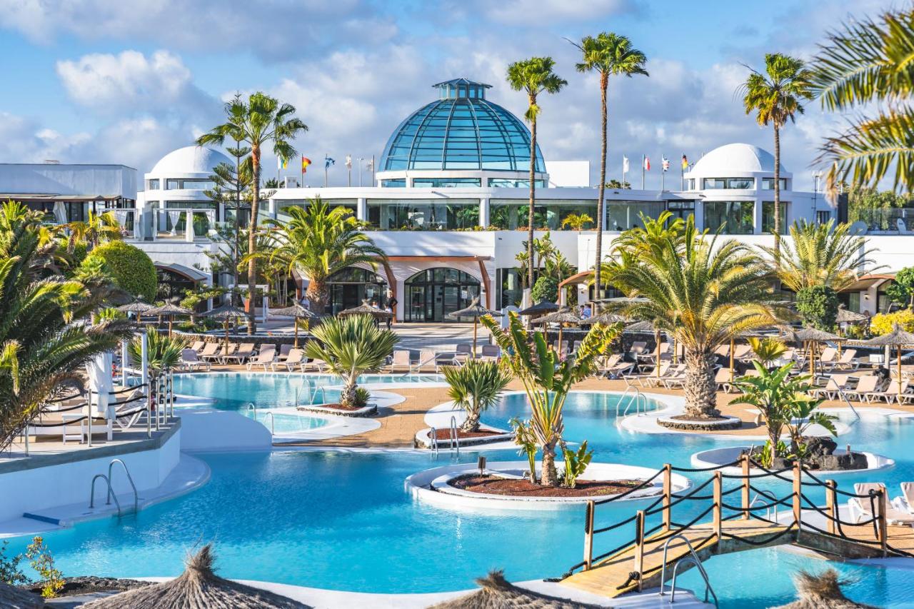 een uitzicht op een resort met palmbomen en een zwembad bij Elba Lanzarote Royal Village Resort in Playa Blanca
