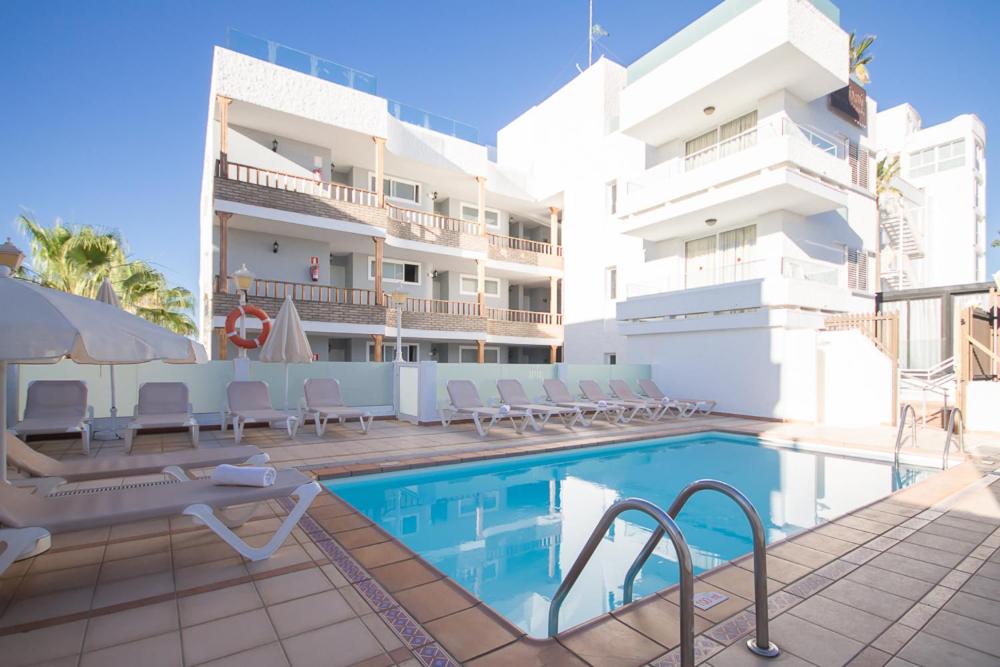 een hotel met een zwembad voor een gebouw bij Apartamentos LIVVO Tarahal in San Agustin