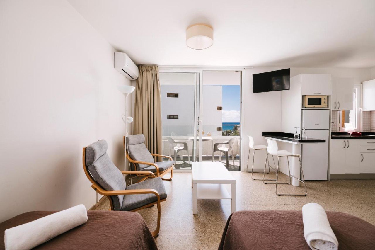 een woonkamer met een bank en stoelen en een keuken bij Apartamentos LIVVO Tarahal in San Agustin