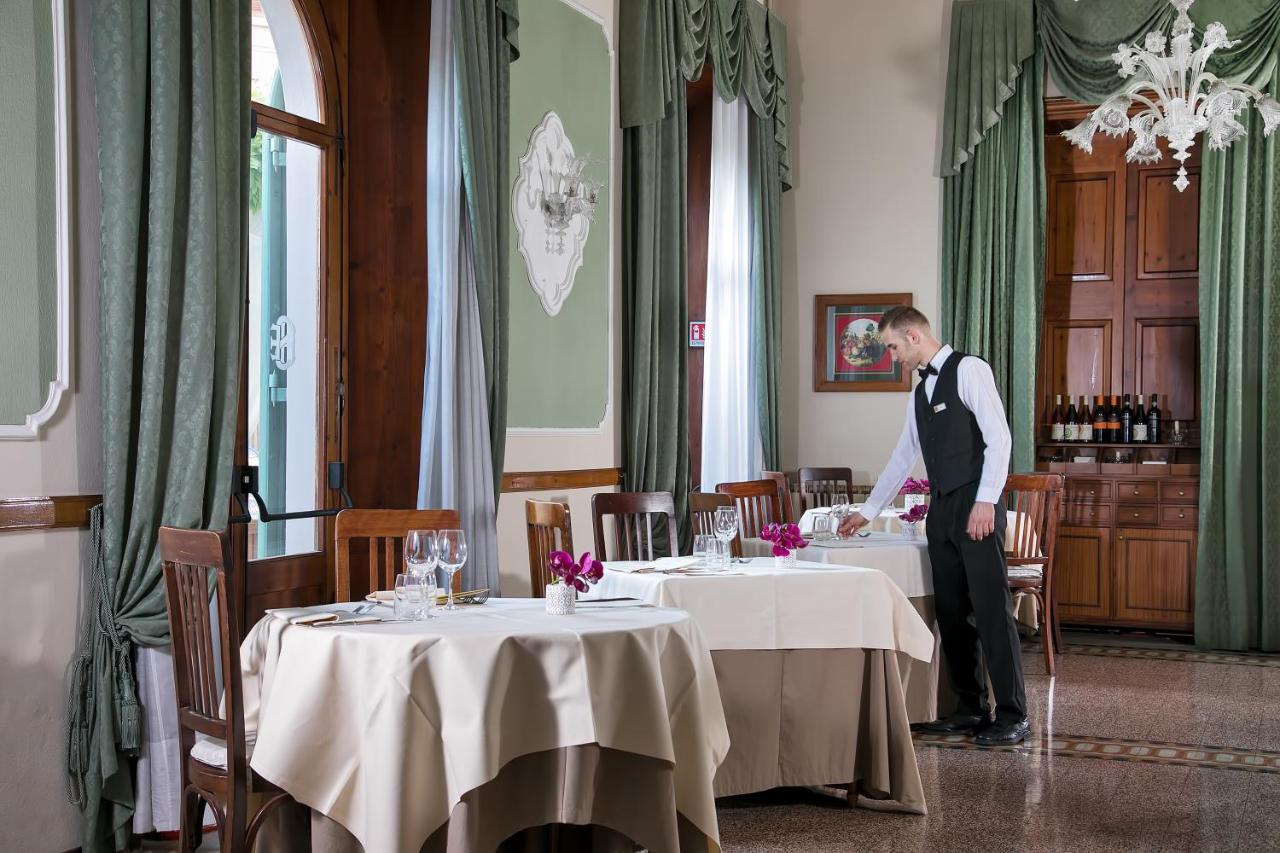 een man die aan een tafel in een eetkamer staat bij Hotel Ercolini & Savi in Montecatini Terme