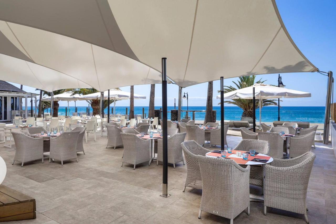 een restaurant op het strand met tafels en parasols bij SOL by Meliá Lanzarote All Inclusive in Puerto del Carmen