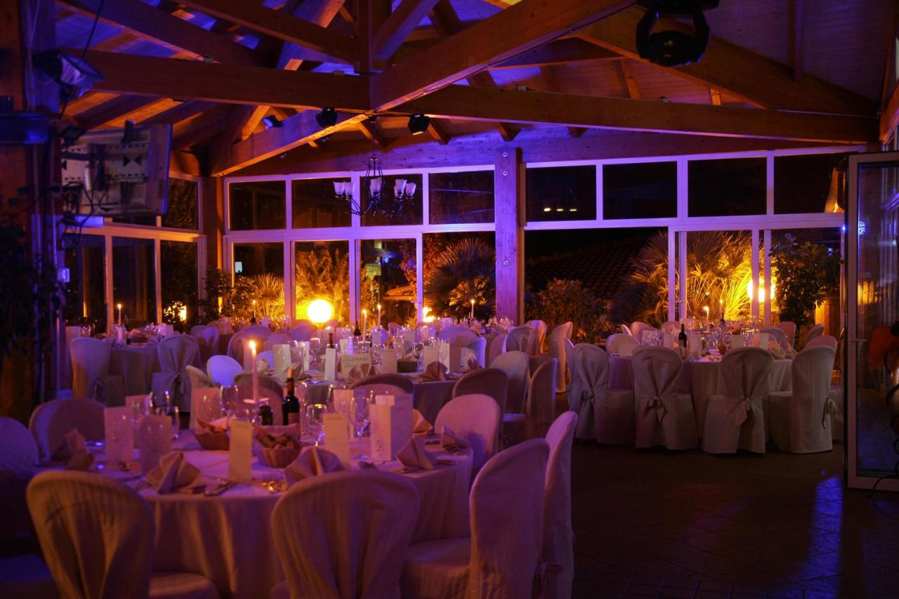 een feestzaal met witte tafels en stoelen en verlichting bij Il Pelagone Hotel & Golf Resort Toscana in Gavorrano