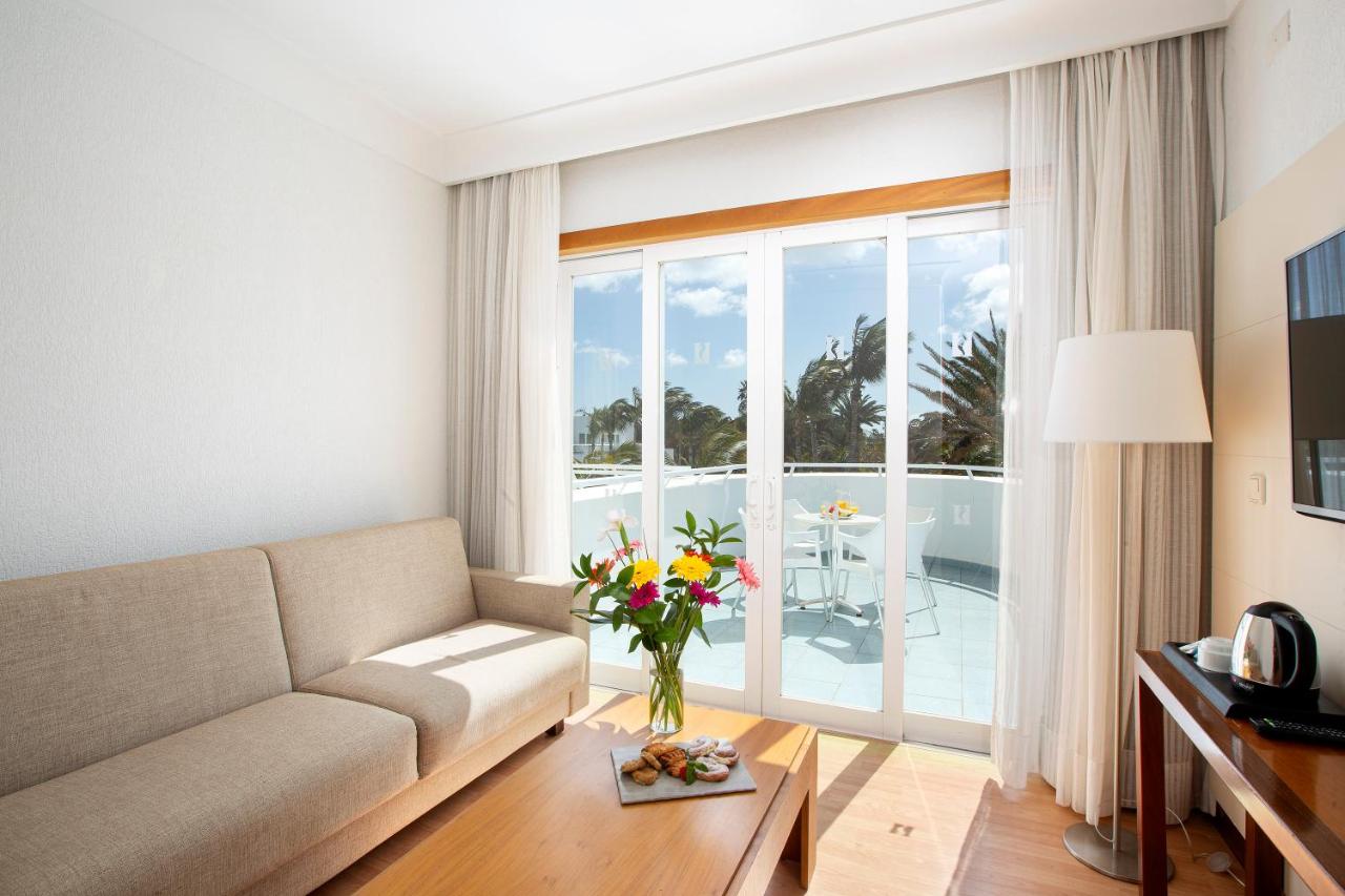 een woonkamer met een bank en een groot raam bij Hipotels La Geria in Puerto del Carmen
