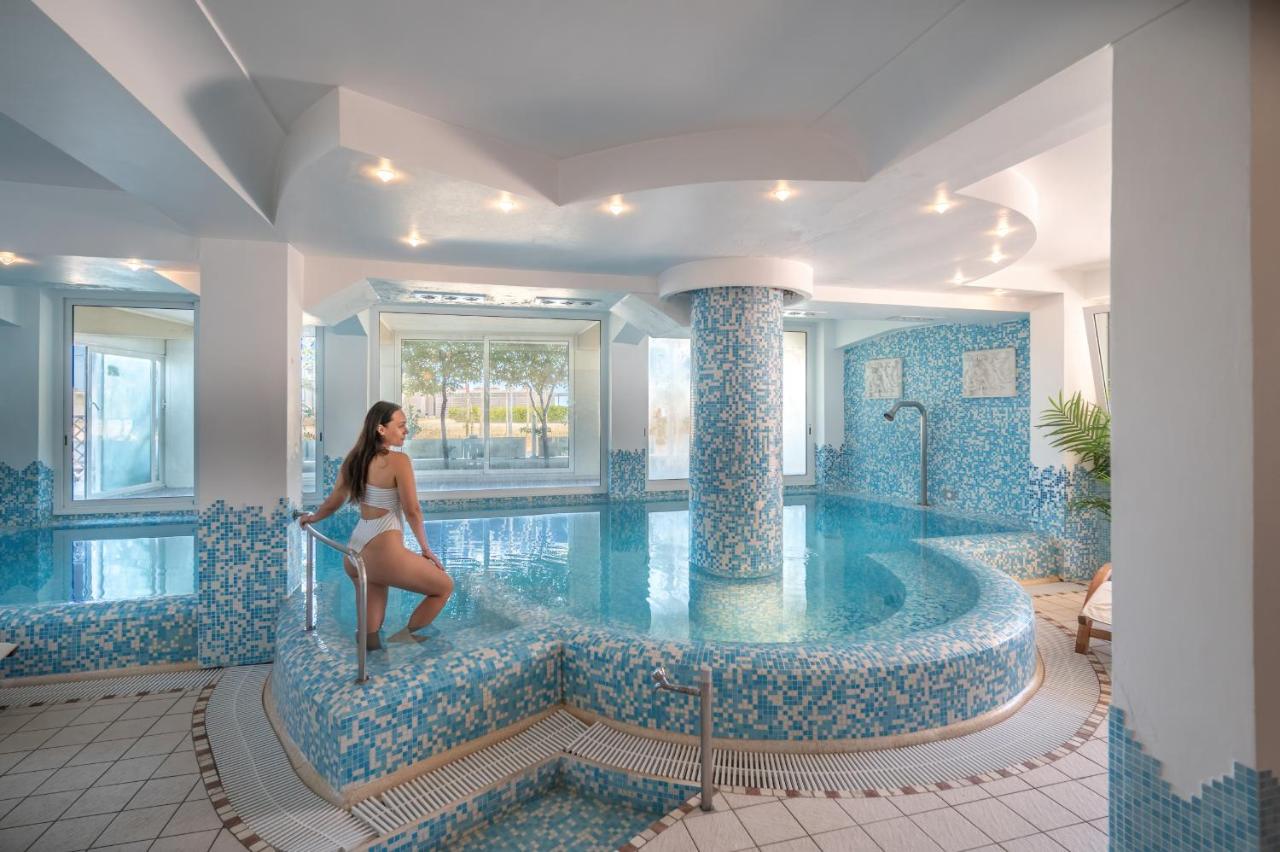 een vrouw in badpak die aan de rand van een zwembad staat bij Hotel Baia Imperiale in Rimini