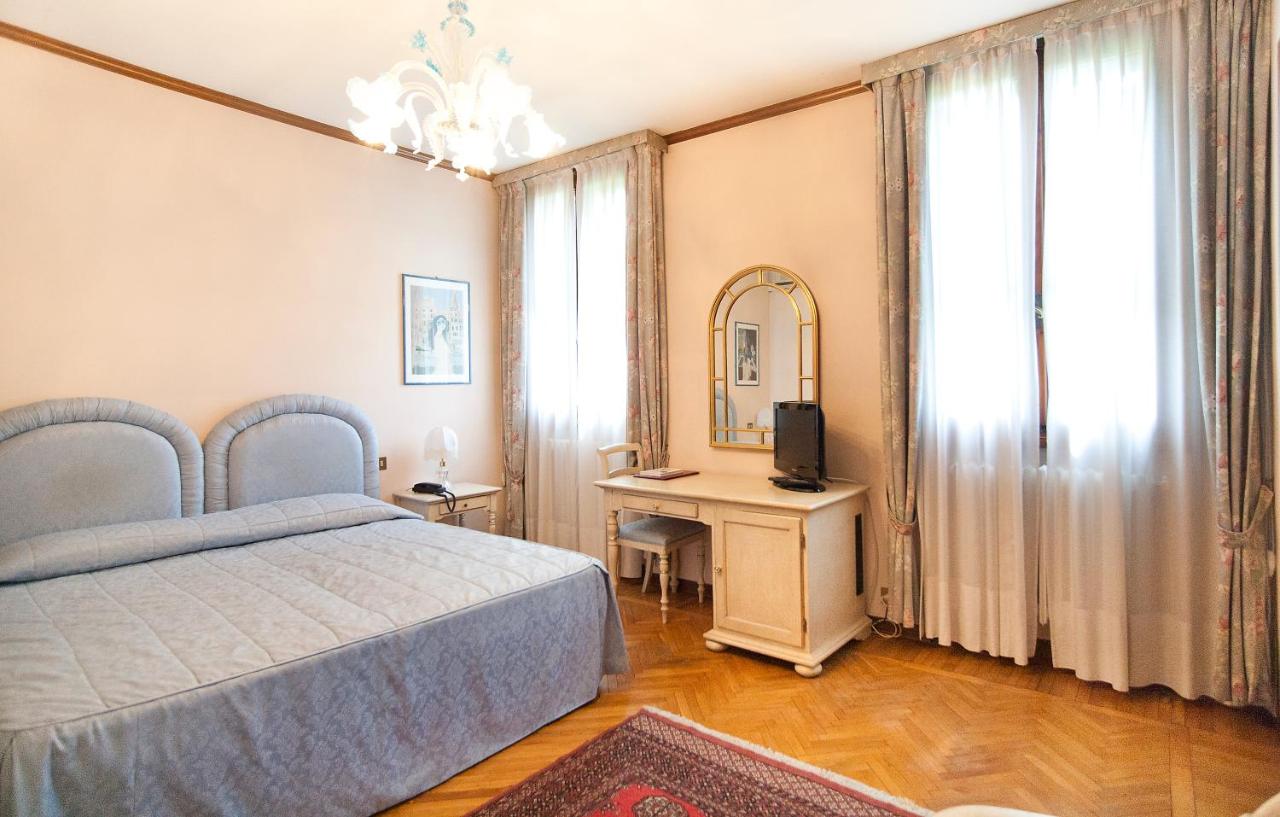 een slaapkamer met een bed en een tafel met een spiegel bij Park Hotel Villa Giustinian in Mirano