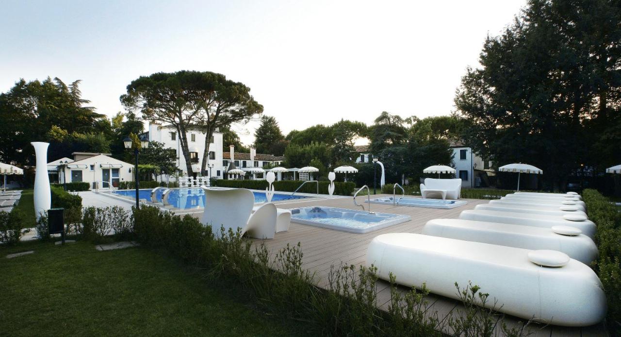 Een rij witte opblaasfiguren staat opgesteld naast een zwembad. bij Park Hotel Villa Giustinian in Mirano
