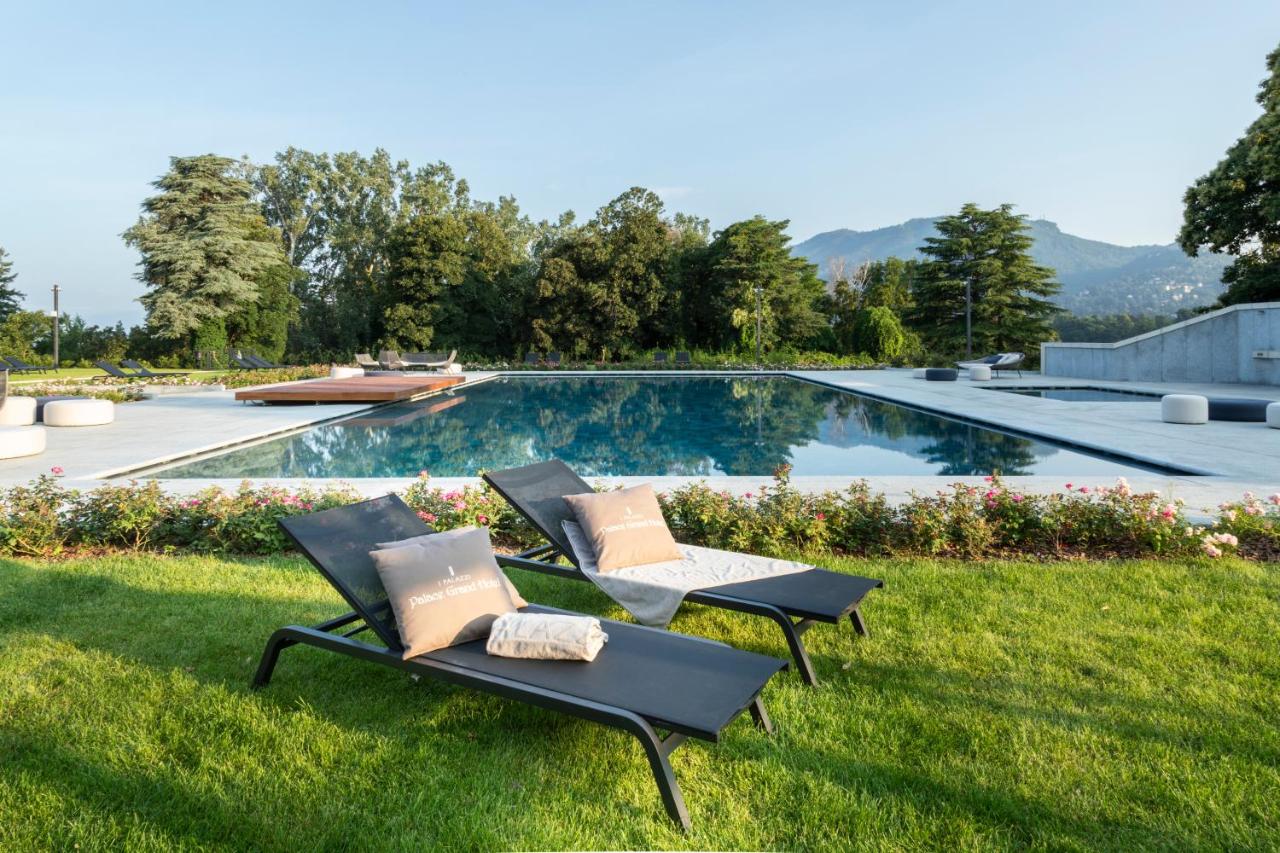 twee ligstoelen op het gras naast een zwembad bij Palace Grand Hotel Varese in Varese