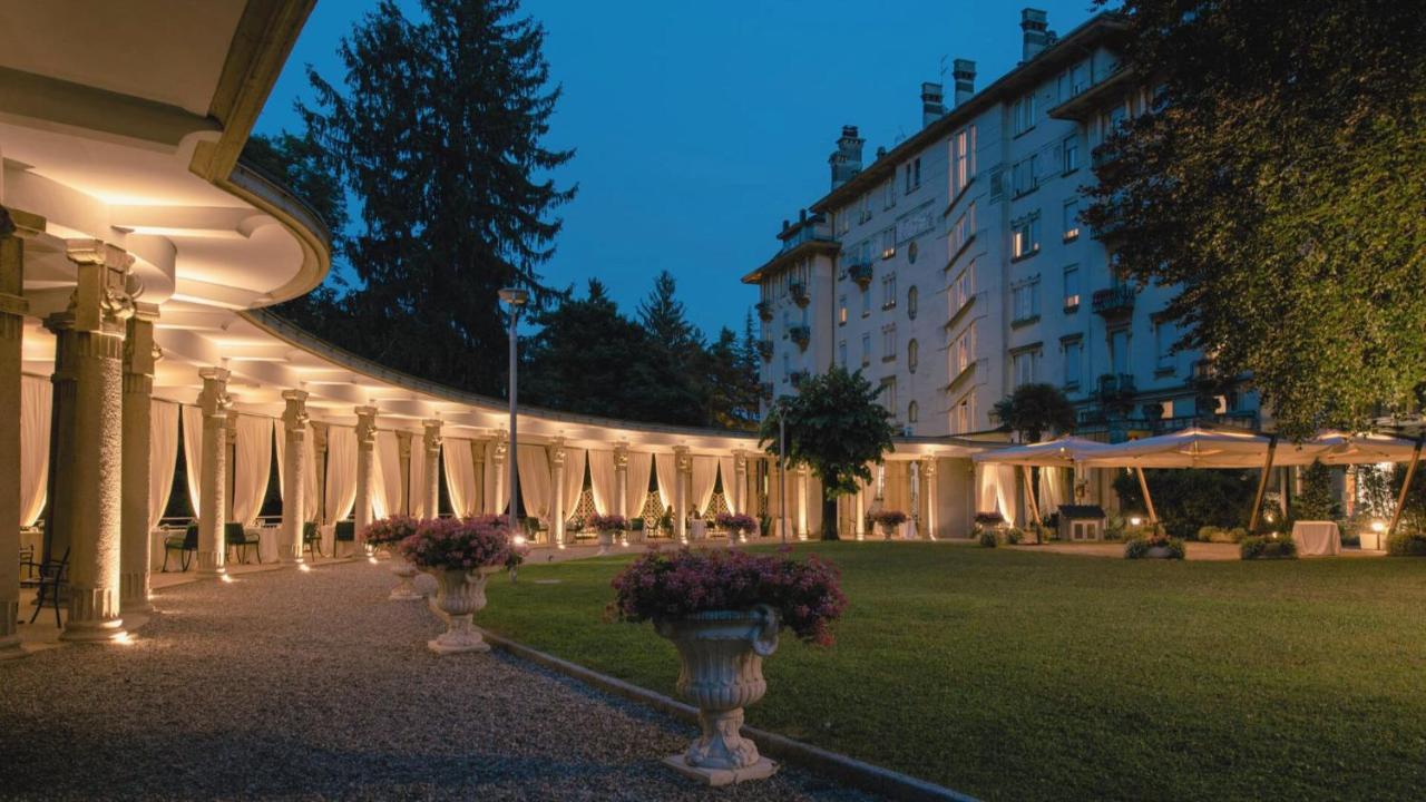 een verlicht gebouw met vazen vol bloemen in een park bij Palace Grand Hotel Varese in Varese +146 foto's