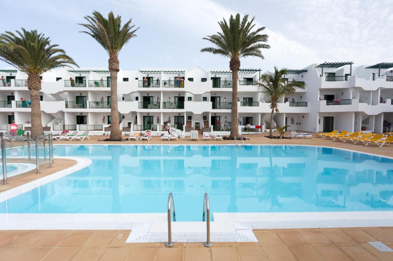 een groot zwembad met palmbomen voor een gebouw bij Apartamentos Acuario Sol in Puerto del Carmen