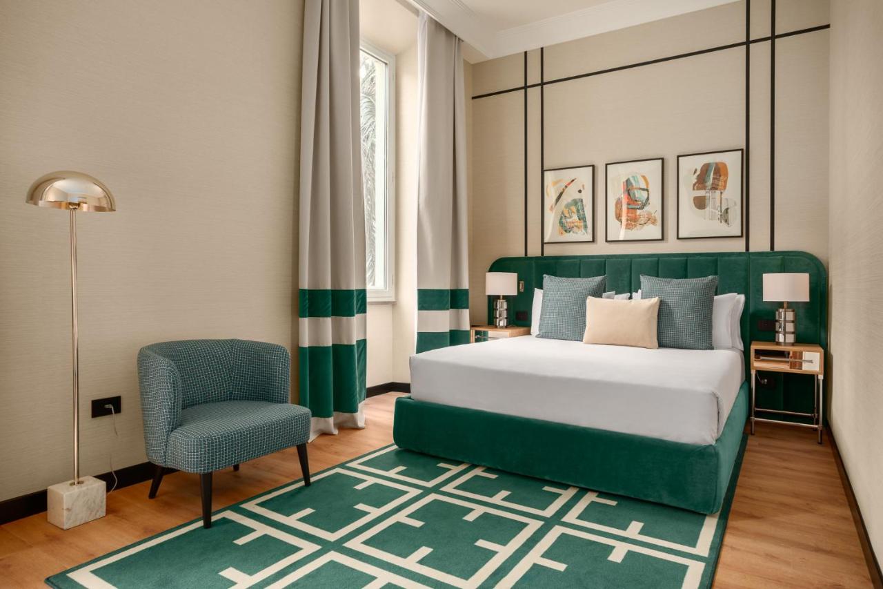 een slaapkamer met een groen bed en een stoel bij Room Mate Collection Mia, Rome Colosseum in Rome
