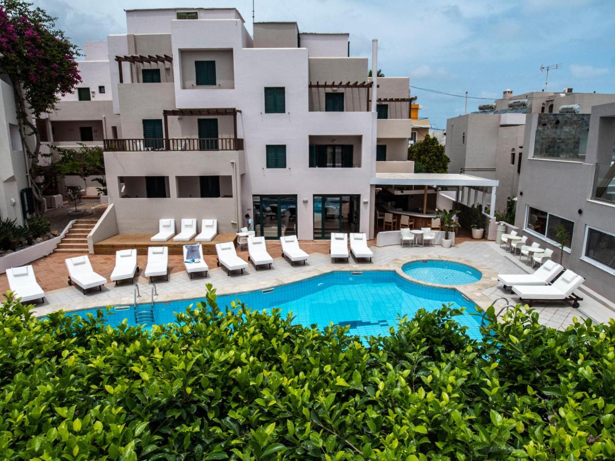 een appartement met een zwembad en ligstoelen en een gebouw bij Porto Greco Village Beach Hotel in Chersonissos
