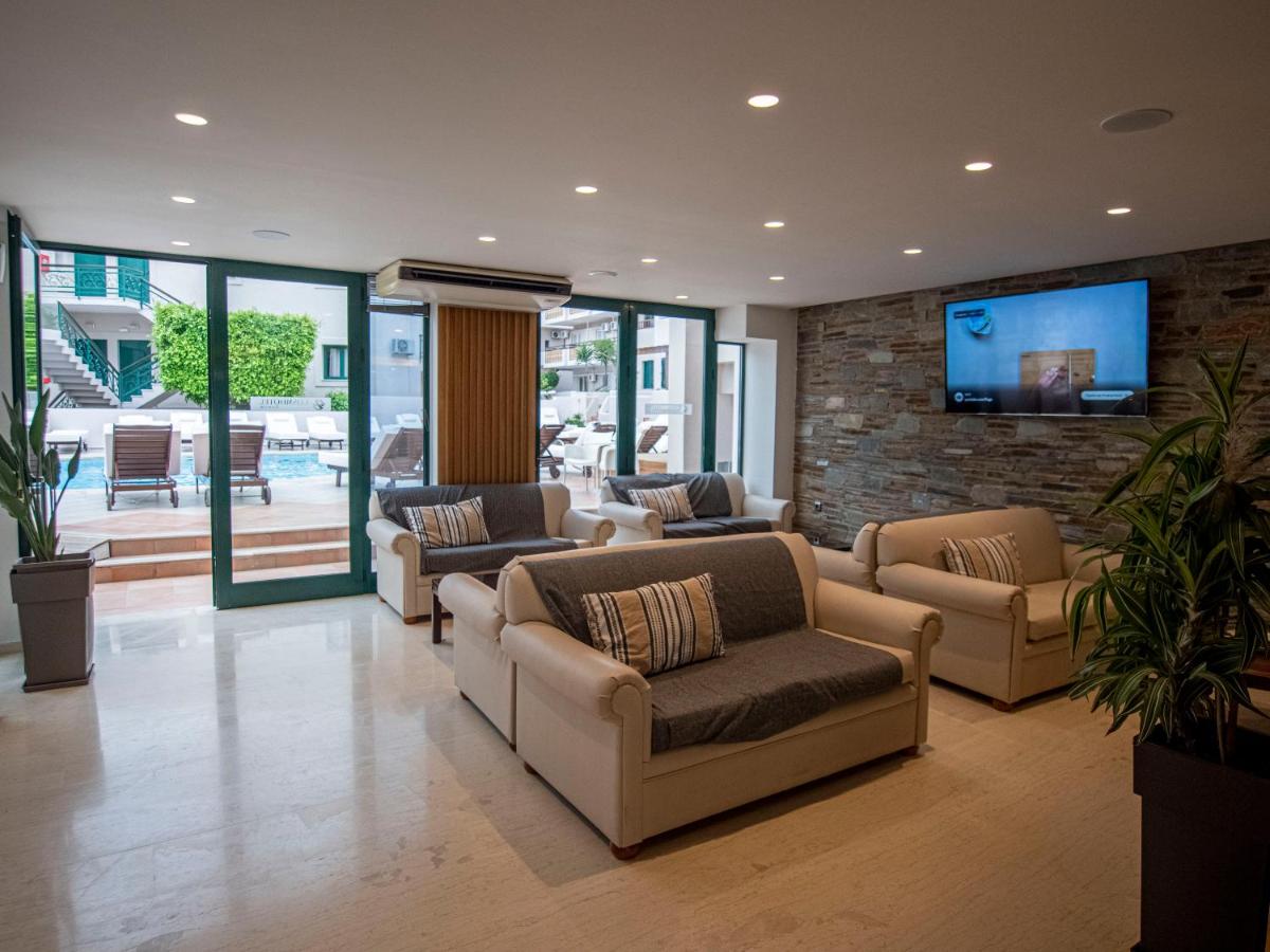 een woonkamer met banken en een tv tegen een bakstenen muur bij Porto Greco Village Beach Hotel in Chersonissos