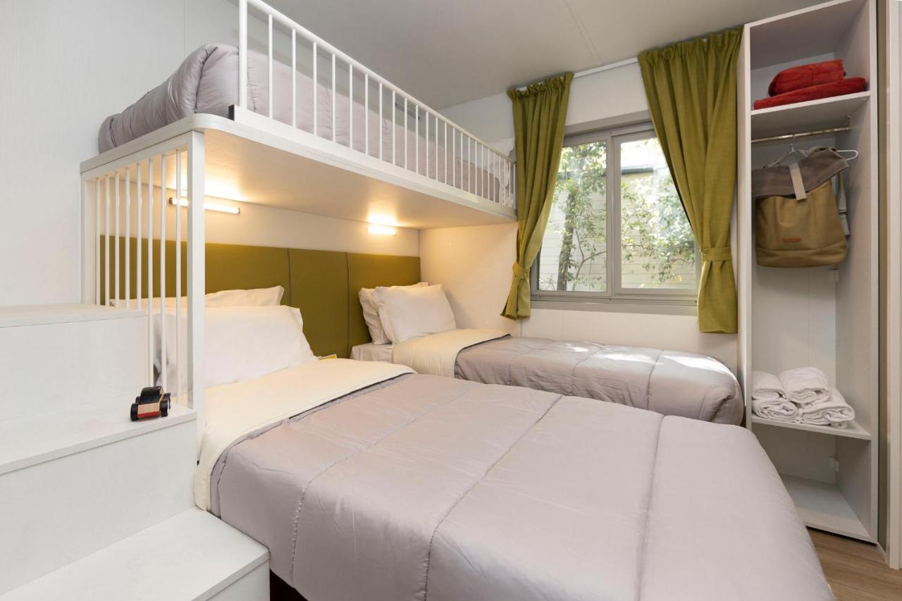 een slaapkamer met twee eenpersoonsbedden en een stapelbed bij hu Park Albatros village in San Vincenzo
