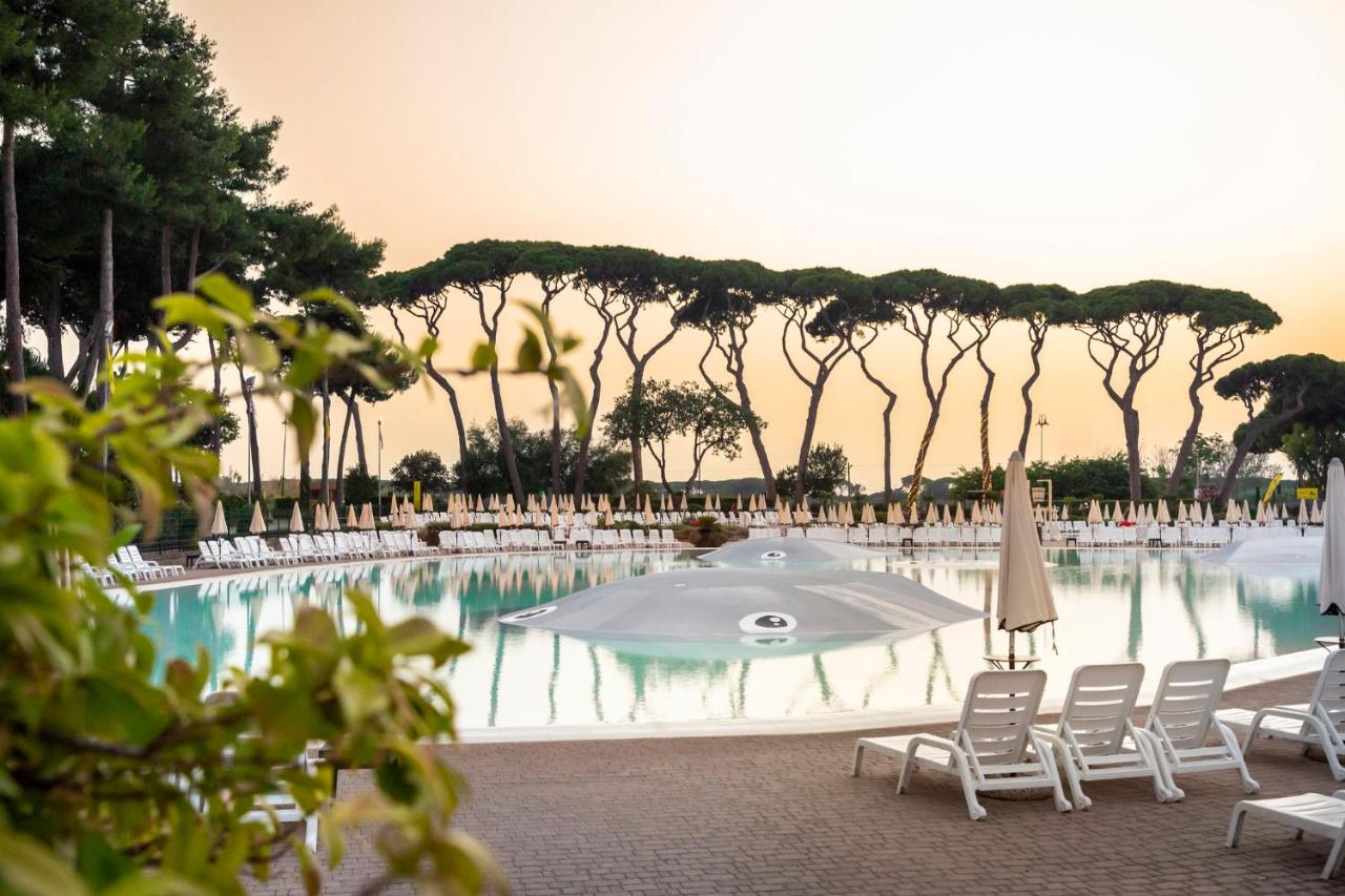 een zwembad met stoelen en een parasol en bomen bij hu Park Albatros village in San Vincenzo