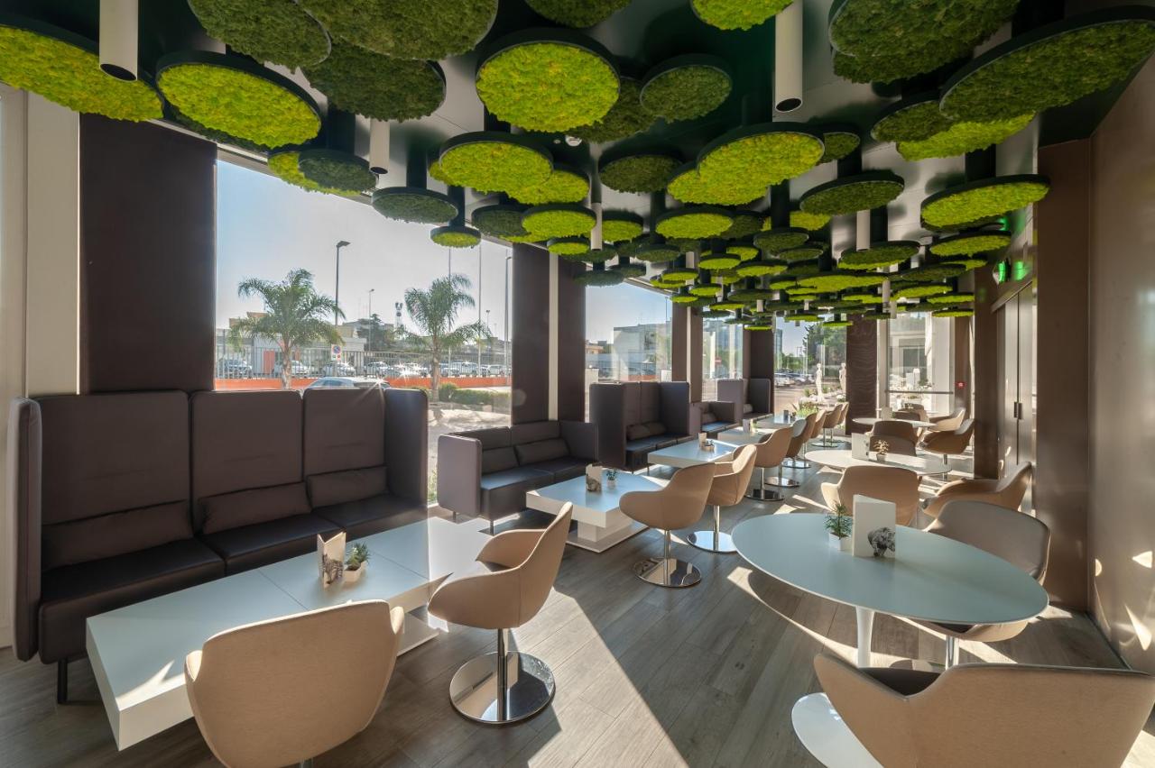 een wachtkamer met tafels en stoelen en grote ramen bij 8Piuhotel in Lecce