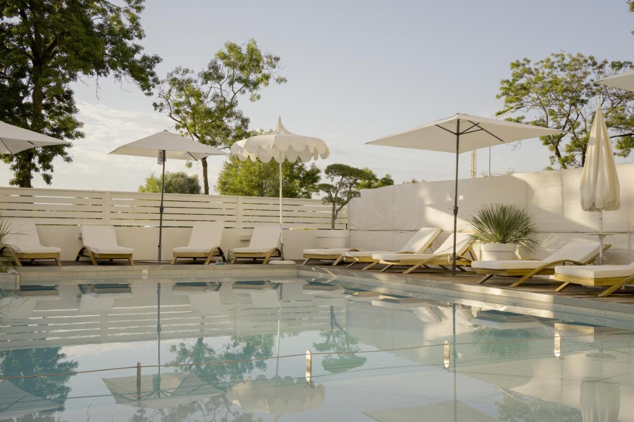 een zwembad met ligstoelen en parasols bij Hotel President in Lido di Jesolo