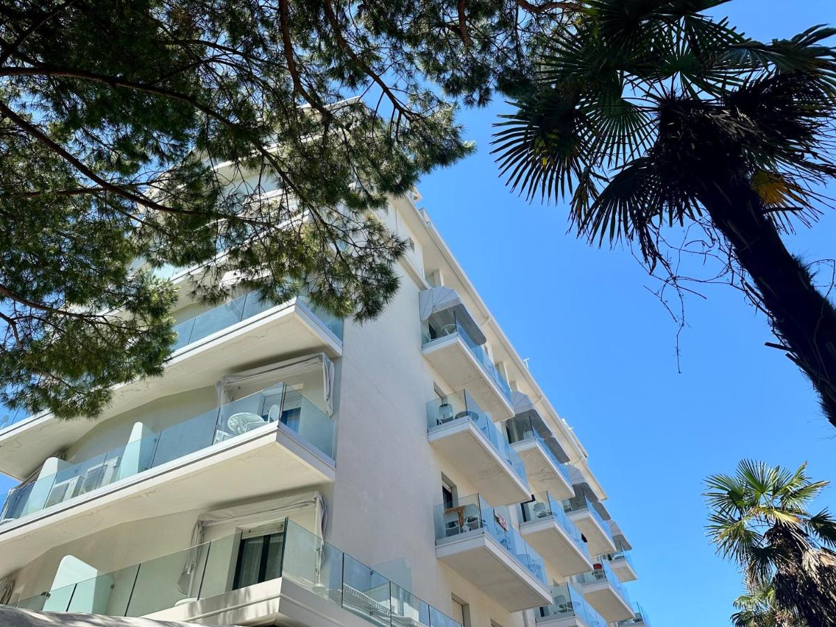 een appartementencomplex met witte balkons en een palmboom bij Hotel President in Lido di Jesolo