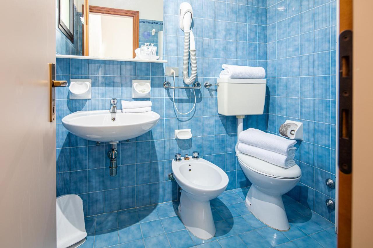 Een badkamer met blauwe tegels, een toilet en een wastafel. bij Hotel Astor in Lido di Jesolo
