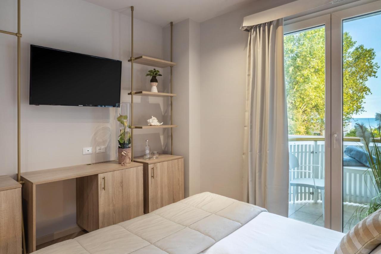 een slaapkamer met een bed, een tv en een balkon bij Salus Smart & Chic Hotel in Lido di Jesolo