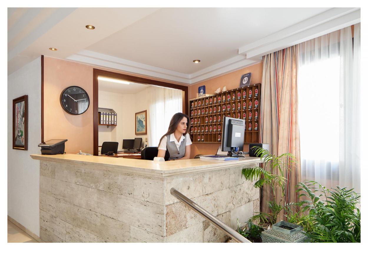 een vrouw die achter een receptiebalie in een bibliotheek zit bij Hotel Ninays in Lloret de Mar