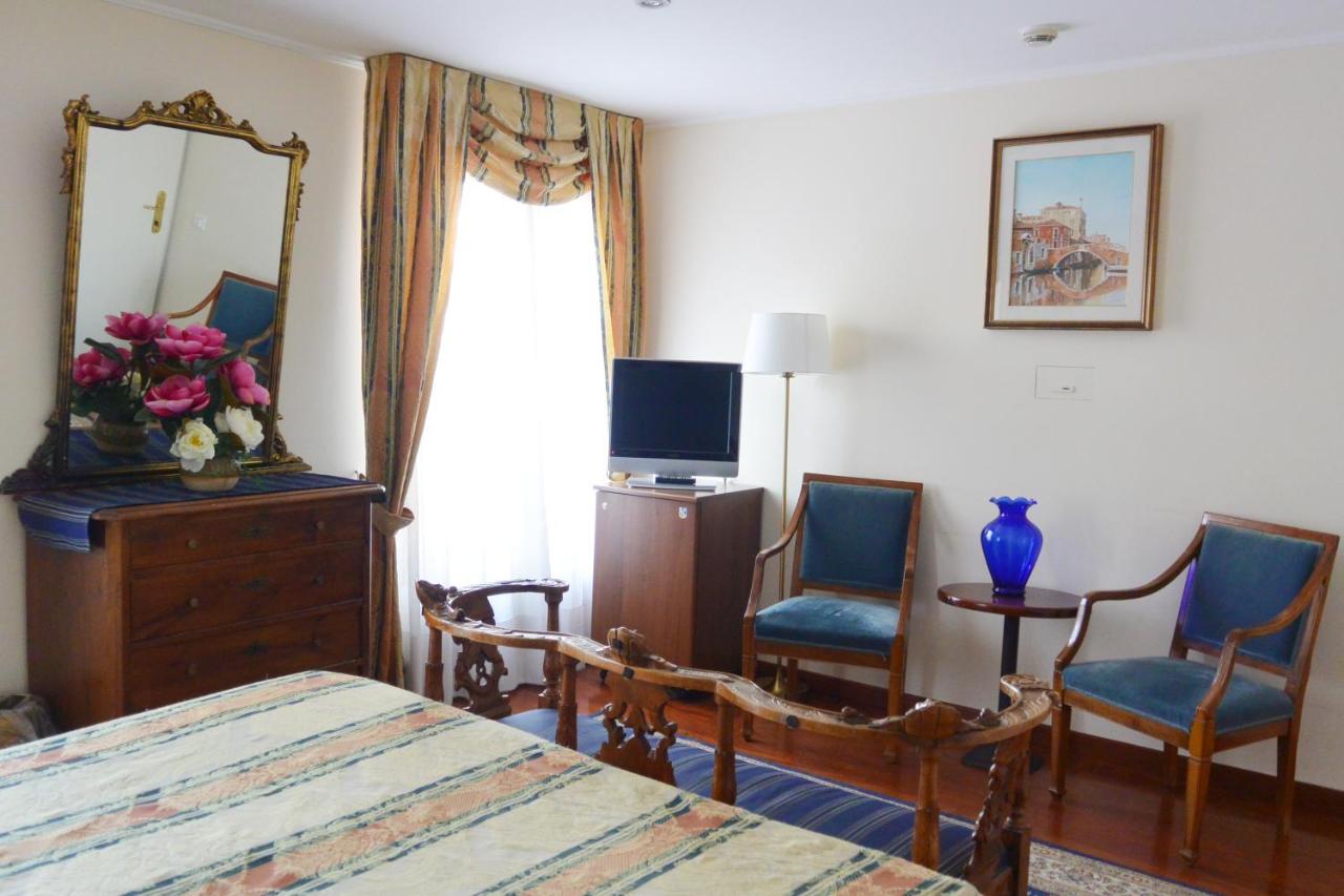 een slaapkamer met een bed, twee stoelen en een spiegel bij Hotel San Zulian in Venetië