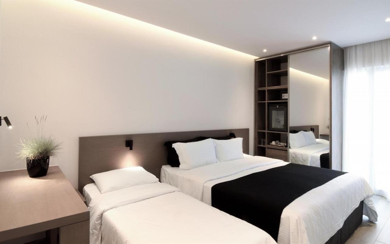 een hotelkamer met twee bedden en een spiegel bij Poseidon Athens Hotel in Athene