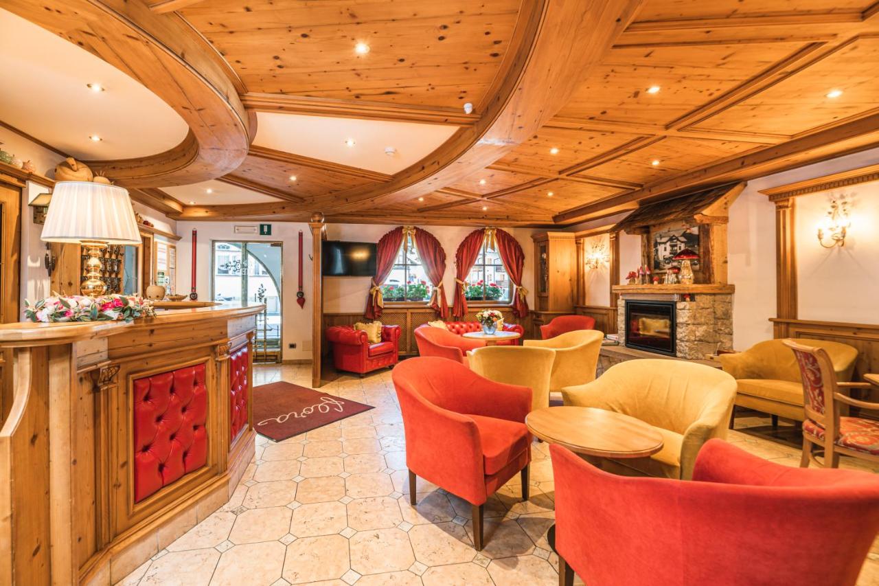 een woonkamer met rode stoelen en een tafel bij Hotel Flora in Selva di Val Gardena