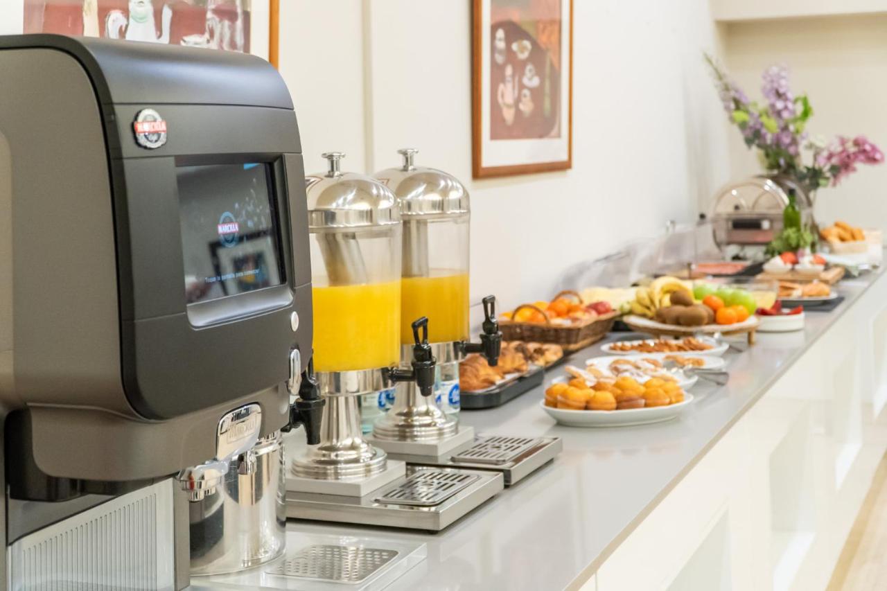 een ontbijtbuffet met sinaasappelsap en schalen met eten bij Hotel Glòries in Barcelona